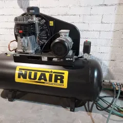 Un compresor de uña NUAIR, negro, con etiqueta amarilla y detalles plateados. Ideal para tu taller.