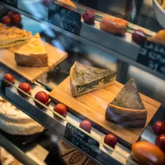 W witrynie chłodniczej kuszą dania lotniska: kawałki quiche, ciasta i lasagne. Obok piętrzą się pomidorki koktajlowe.