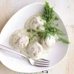 Pyszne pulpety w sosie koperkowym, udekorowane świeżym koperkiem, czekają na talerzu.
