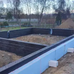 Budowa domu w toku. Widać zbrojenie i izolację fundamentów.