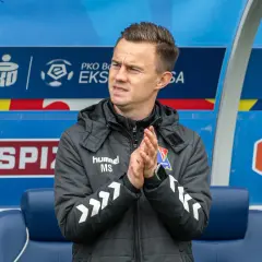 Trener w kurtce z logo PKO BP Ekstraklasy, zastanawia się, gdzie oglądać ekstraklasę za darmo.