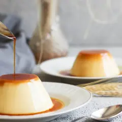 Delicioso flan de huevo con caramelo líquido cayendo de una cuchara. Una receta casera que enamora.