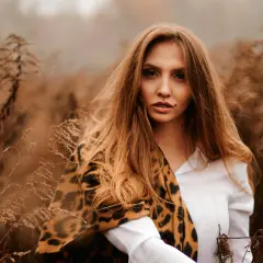 Kobieca sesja jesienna w otoczeniu suchych traw. Długie, falujące włosy i wzorzysty szal dodają jej dzikiego uroku.