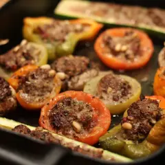 Délicieux légumes farcis, tomates, poivrons et courgettes, garnis d'une savoureuse farce à la viande et aux pignons.