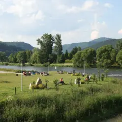 Relaks nad Dunajcem w Krościenku. Ludzie odpoczywają na trawie, w tle góry i rzeka. To świetne krościenko nad dunajcem atrakcje.
