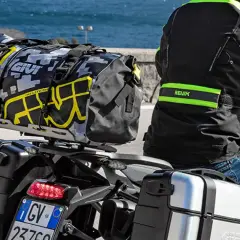 Motociclista con equipaje en maletas laterales y bolsa trasera. Es correcto transportar el equipaje en maletas laterales para viajes largos.