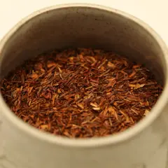 Czerwona herbata rooibos w ceramicznym kubku, idealna na relaksujący wieczór.