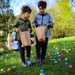 Deux enfants cherchent des œufs colorés dans l'herbe lors d'une chasse aux œufs à Paris.