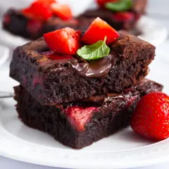 Pyszne brownie z truskawkami, polane czekoladą i ozdobione świeżymi owocami. Idealne na deser.