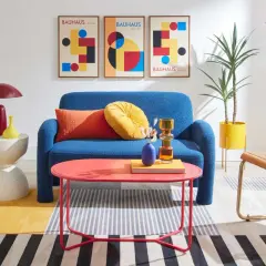 A living room showcasing bauhaus design examples: blue sofa, geometric art, and colorful accents.