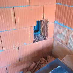 Otwór w ścianie z pustaków ceramicznych, przygotowany pod wentylację garażu przez ścianę.
