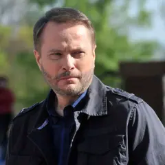 Artur Żmijewski, który gra Ojca Mateusza, w ciemnej kurtce i kratowanej koszuli, zamyślony.