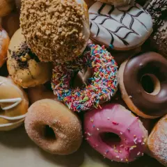 Kolorowe pączki z posypką, lukrem i cukrem pudrem. Każdy pączek to mała przyjemność, ale warto pamiętać o jego pączek kcal.