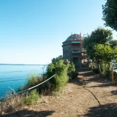 Sentiero panoramico verso un edificio storico sull'isola Bisentina. La visita è un'esperienza suggestiva tra natura e storia.