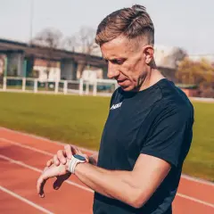 Biegacz sprawdza czas na zegarku na bieżni. To jego maraton czas amatora, liczy się każdy krok.