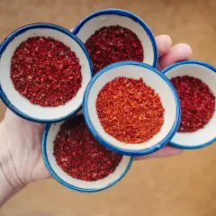 Cztery małe miseczki z gochugaru, koreańską papryką chili. To właśnie gochugaru co to za przyprawa, która nadaje potrawom pikantności i koloru.