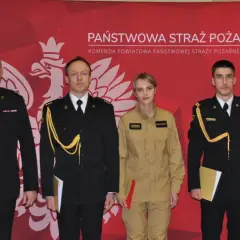 Czterech funkcjonariuszy Państwowej Straży Pożarnej w galowych mundurach i kombinezonie, z odznaczeniami i dokumentami.