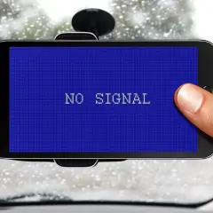 Smartfon w uchwycie samochodowym pokazuje komunikat "NO SIGNAL". Problem z GPS w deszczowy dzień.
