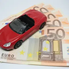Czerwony samochodzik na banknotach 50 euro. Koszt zakupu auta i podatek PCC-3.