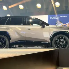 Nowe Toyota RAV4 opinie: elegancki SUV na scenie, z ekranem pokazującym ładowanie.
