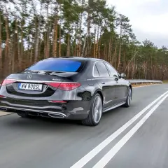 Czarny Mercedes S400d 4Matic sunie po drodze wśród drzew.