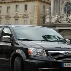 Czarny Lancia Voyager na tle zabytkowej architektury.