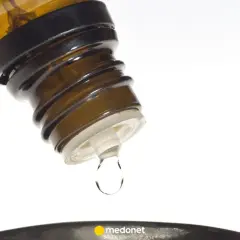 Kropla leku, jak zyrtec krople, spada z brązowej buteleczki.
