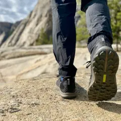 Close-up of hiking boots on a rocky trail, showcasing the aggressive boot tread patterns designed for grip on uneven terrain.