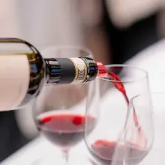 Versando vino rosso da una bottiglia in calici, un'esperienza dei migliori vini Chianti.