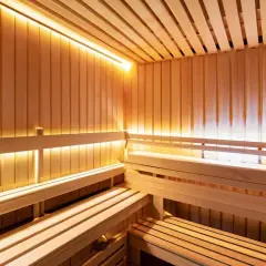 Drewniana sauna z ławami i ciepłym, nastrojowym oświetleniem. Lampy do sauny tworzą relaksującą atmosferę.