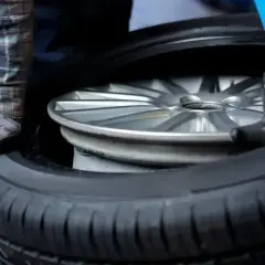 Mechanik w warsztacie wymienia oponę na feldze. Zastanawiasz się, ile kosztuje wymiana opon?