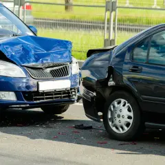 Wypadek drogowy. Niebieski i czarny samochód po kolizji. Widać uszkodzenia, poduszki powietrzne. Zasada 3 sekund nie została zachowana.