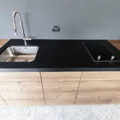 Mobile lavello cucina fai da te con piano in pietra nera, piano cottura a induzione e rubinetto cromato.