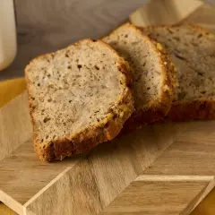 Tre skivor bananbröd på en träskärbräda. Perfekt för att se om man kan frysa om bröd och njuta av senare.