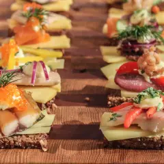Reihe von appetitlichen Smørrebrød mit Fisch, Kaviar und Gemüse – perfektes schnelles Fingerfood für jeden Anlass.