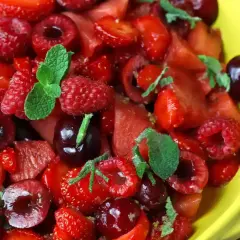 En härlig vattenmelon sallad med jordgubbar, hallon och körsbär, toppad med mynta. Perfekt för en varm sommardag.