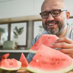 Glücklicher Mann mit Brille isst Wassermelone. Wenige kalorien Wassermelone ist ein gesunder Snack.