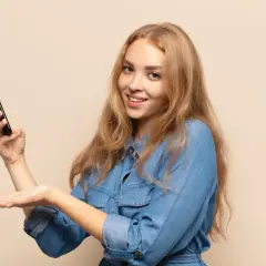 Uśmiechnięta blondynka trzyma telefon, prezentując etykietę cyfrową InPost.