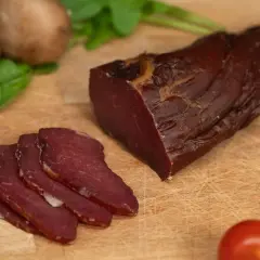 Filet mignon fumé, tranché, prêt pour le temps de fumage. Champignons et tomates en arrière-plan.