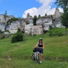 Kobieta z rowerem na tle ruin zamku na Szlaku Orlich Gniazd.