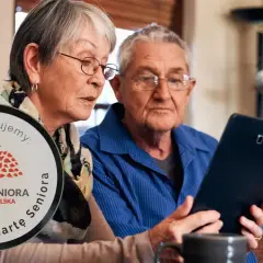 Para dowiedzieć się, jak zdobyć Kartę Seniora, starsza para wspólnie przegląda informacje na tablecie.