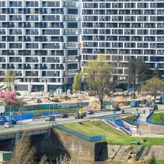 Nowe mieszkania do wynajęcia Rzeszów. Nowoczesne apartamentowce w budowie, ruchliwa droga i most.