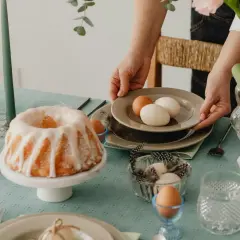 Tavola apparecchiata per Pasqua con un ciambellone glassato, uova e decorazioni. I dolci pasquali sono pronti per essere gustati.