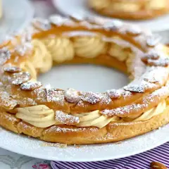 Un Paris-Brest, pâtisserie en forme de couronne, garni d'une crème onctueuse et saupoudré d'amandes effilées et de sucre glace.
