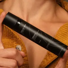 Dłoń trzyma czarny flakon kremu z napisem "NIACINAMIDE". Czy wybrać retinol czy niacynamid?