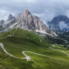 Kręta droga na Passo Giau w Dolomitach, otoczona zielonymi wzgórzami i skalistymi szczytami.