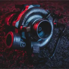 Turbosprężarka po regeneracji, gotowa do montażu. Ciemne tło z czerwonymi akcentami podkreśla jej moc.