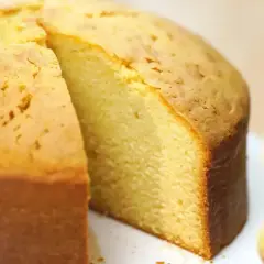 En saftig, gyllene glutenfri tårtbotten med en bit borttagen, som visar den fluffiga insidan. Perfekt för alla tillfällen.