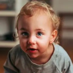 Niebieskie, uciekające oko dziecka z blond lokami, patrzy z zaciekawieniem.