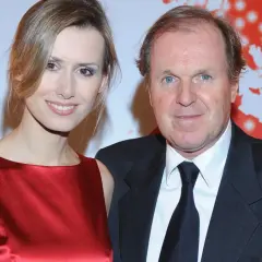 Wojciech Fibak z partnerką. Uśmiechnięta para na tle czerwonej mapy świata.